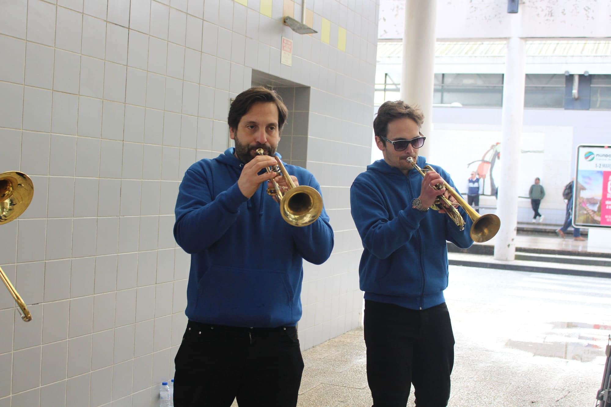Trompete e saxofone a tocar lado a lado num átrio de azulejos